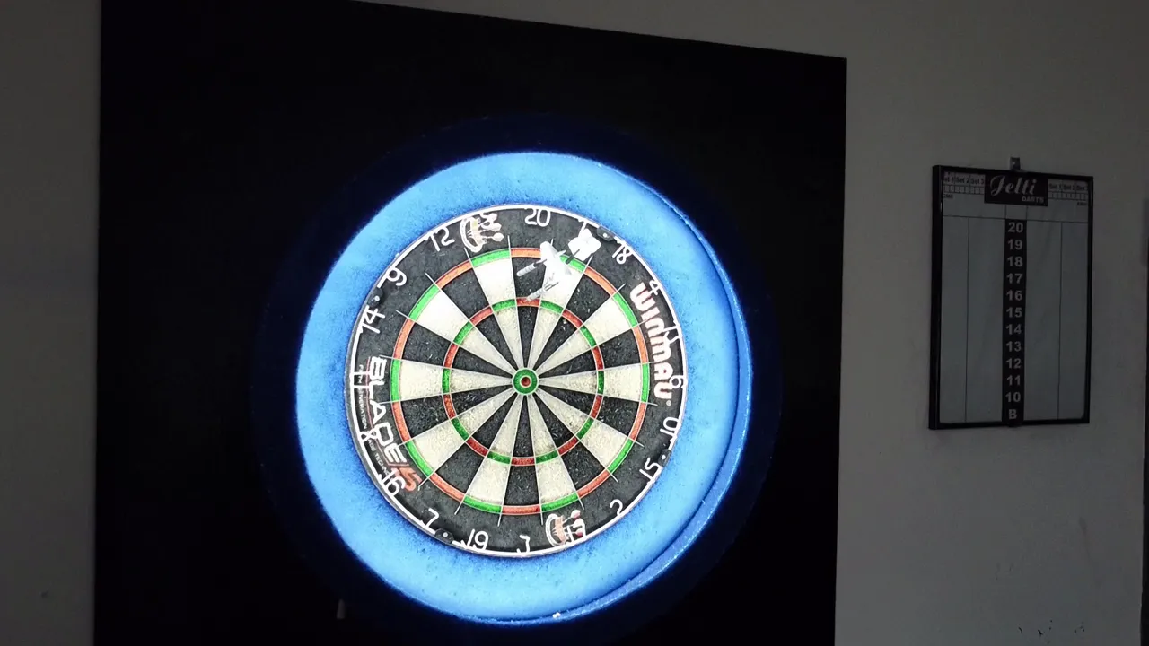 Een verlicht dartbord met blauwe ring op een van de twee dartbanen van Café De Statie